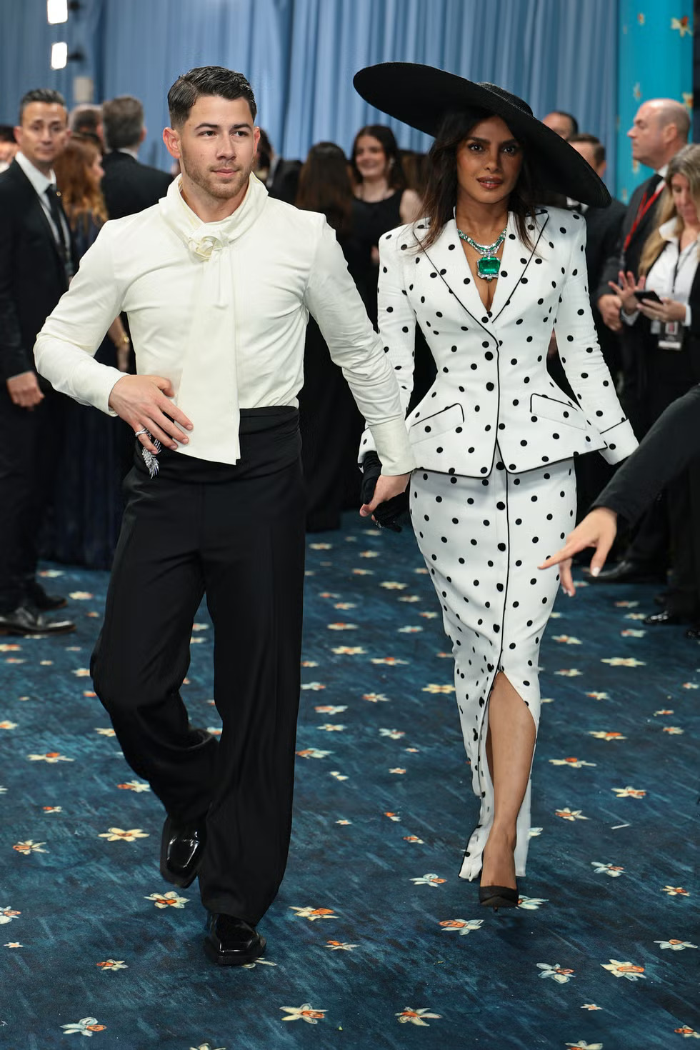 Priyanka Chopra in a white polka-dot Balmain gown and oversized black hat with Nick Jonas in monochrome at the 2025 Met Gala